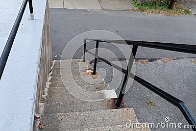 Descending flight of exterior concrete stairs with recently painted black pipe railing, narrow steps to street level Stock Photo