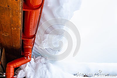 The descent from the roofs of the snow. A large snowdrift of melting snow with icicles rolls down from the roof Stock Photo