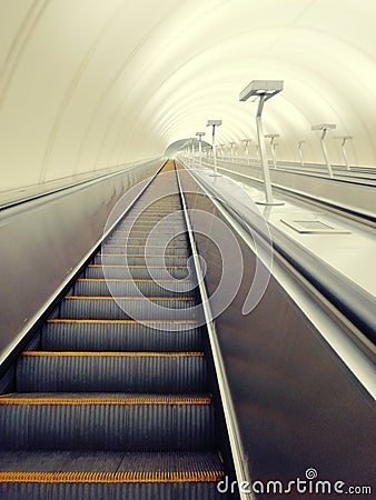 Descent into the tunnel stereo escalator stairs light from below. Modern tunnel escalator electronic system moving vintage style, Stock Photo