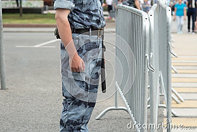 A policeman with a baton near the metal fence, close-up Stock Photo