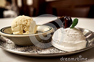 Sweet dessert assorted with icecreams topped with chocolate pecan on a plate sprinkeld with sugar powder Stock Photo