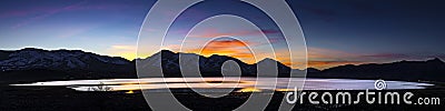 Desert lake, flooded playa at Sunset with mountain ranges and colorful clouds. Stock Photo