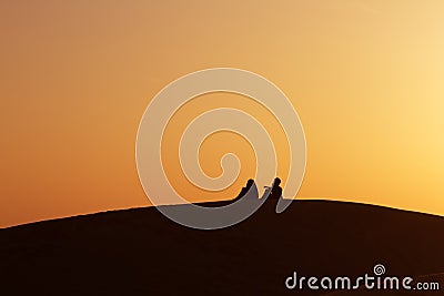 Desert nomads on the crest of a barchan at sunset Stock Photo