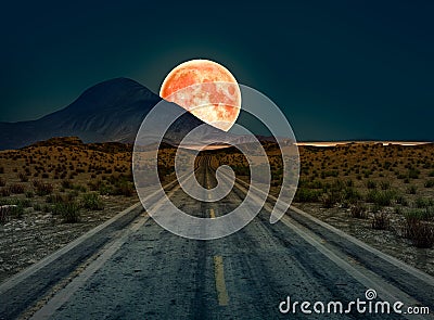 A desert road at night leading off into infinity with a huge full moon Stock Photo