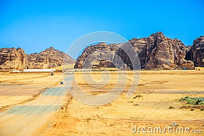 Desert sand landscape with mountains in the background and road with cars, near Al Ula, Saudi Arabia Stock Photo