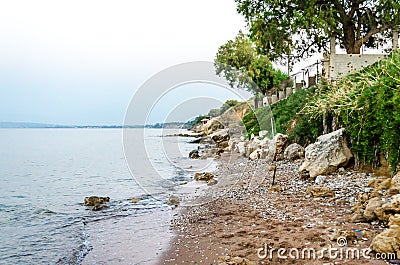 Deserted Beach with Calm Sea and Coast with Pebbles, Sand and Rocks in Greece at Sunset. Isolated Place with No People Stock Photo
