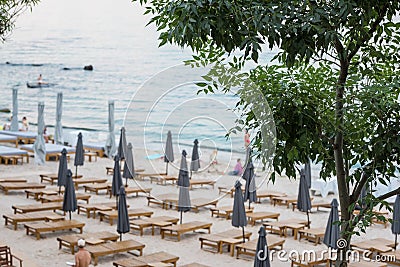 Deserted beach with sun loungers and folded umbrellas Stock Photo