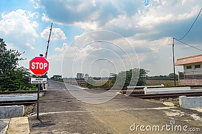 a deserted railroad crossing with no vehicles passing by. Translation on sign text 
