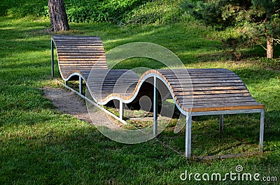 Design bench in the shape of a wavy line. wooden paneling on a metal galvanized frame. The bench is atypical to order in a city pa Editorial Stock Photo