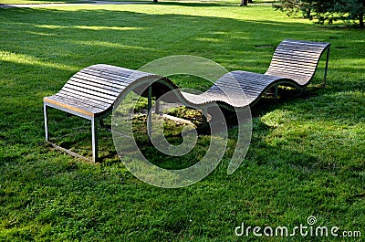 Design bench in the shape of a wavy line. wooden paneling on a metal galvanized frame. The bench is atypical to order in a city pa Editorial Stock Photo