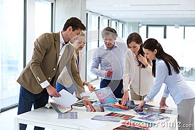 Design professionals with catalogs having discussion at table in new office Stock Photo