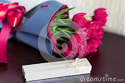 Designed bouquet of fresh brigh pink tulips with a gift box on light green background Stock Photo