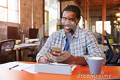 Designer Sitting At Meeting Table Texting On Mobile Phone Stock Photo