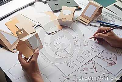 Designer sketching drawing design Brown craft cardboard paper product eco packaging mockup box development template package Stock Photo