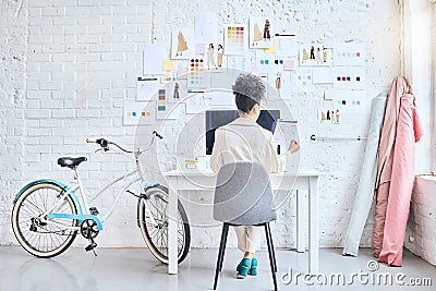Designer woman, workshop and desk by wall, moodboard and reading documents with sketch, planning or idea. Startup Stock Photo