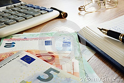 Desk with accountant book, Euros banknotes and calculator. Wealth. Stock Photo