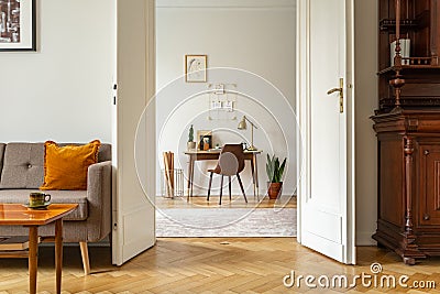 Desk and chair in a home office interior. View through door of a vintage living room. Real photo Stock Photo