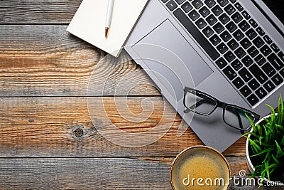 Desk with laptop, eyeglasses, notepad, pen and a cup of coffee on a old wooden table. Top view with copy space. Flat lay. Dark woo Stock Photo