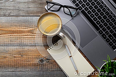 Desk with laptop, eyeglasses, notepad, pen and a cup of coffee on a old wooden table. Top view with copy space. Flat lay. Dark woo Stock Photo