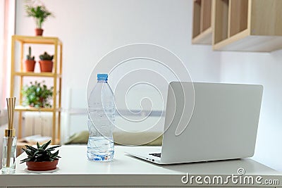 Desk in the room with a laptop and a bottle of water Stock Photo