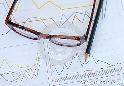 desk workplace, closeup eyeglasses, pencil and report graph on w Stock Photo