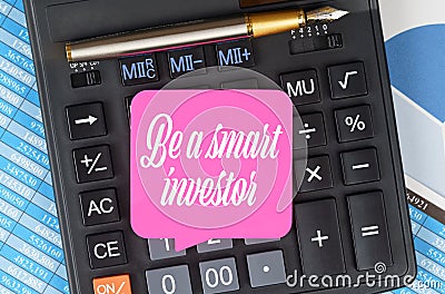 On the desktop are charts, reports, a calculator and a sheet for notes on which it is written - Be a smart investor Stock Photo