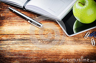 Desktop with paper agenda, digital tablet and green apple Stock Photo