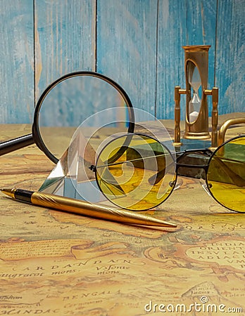 Desktop writing set with an hourglass with a marble base and a crystal pyramid on an ancient map against the background of a Stock Photo