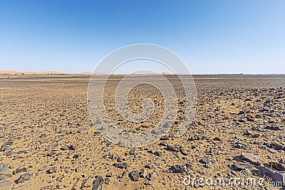 Desolate stone desert in front of the sand dunes of Erg Chebbi Stock Photo