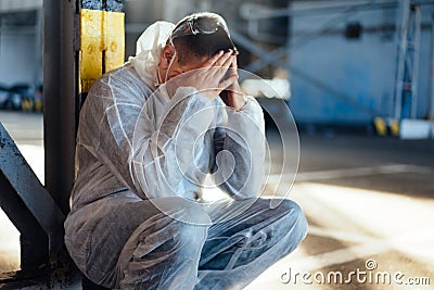 Despair healthcare worker in white covid protective overalls. Tired Male caucasian doctor grabs his head cower in depression Stock Photo