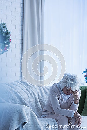 Despair senior woman on sofa Stock Photo