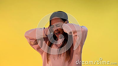 Desperate african woman screaming and covering ears on yellow background Stock Photo