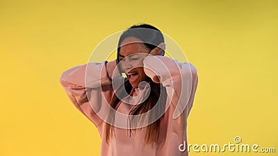 Desperate african woman screaming and covering ears on yellow background Stock Photo