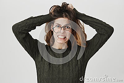 Desperate annoyed female wearing glasses screaming in rage and anger tearing hair out, clenching teeth, while feeling Stock Photo