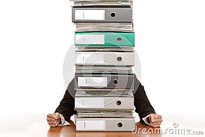 Desperate business woman sits behind folder stack Stock Photo