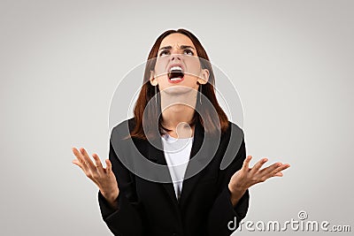 Desperate businesswoman in a black suit looking upwards with hands raised in exasperation Stock Photo