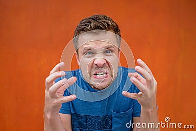 Desperate furious raged man in blue shirt screaming loudly having his eyes full of anger. Stock Photo