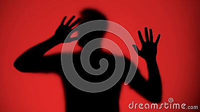 Desperate male silhouette trying to escape from captivity, red background Stock Photo