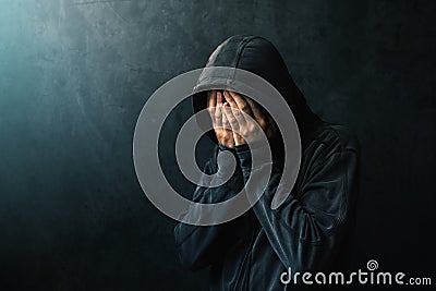 Desperate man in hooded jacket is crying Stock Photo