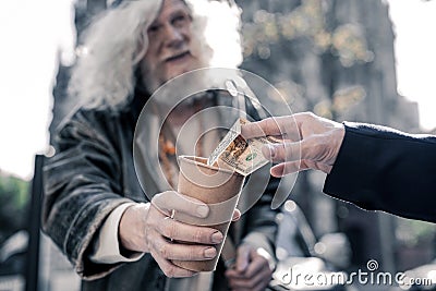 Grey-haired homeless man carrying cardboard cup and begging Stock Photo