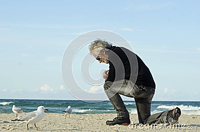 Desperate sad lonely man praying alone on ocean beach Stock Photo