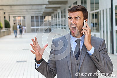 Desperate young brunette businessman get bad news heavy problems, faces challenges snort while talking on the mobile phone Stock Photo