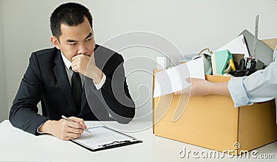 Desperately fired female office worker employee hands her employer her resignation letter and packs her belongings in a cardboard Stock Photo