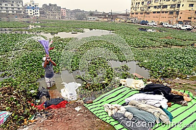 Dirty Laundry: Washerman wash clothes in polluted water Editorial Stock Photo