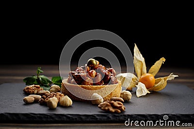 Dessert basket with nuts and caramel, on a black stone Stock Photo