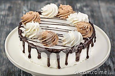 Dessert biscuit cake with white cream, whipped cream and chocolate glaze Stock Photo