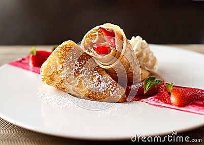 A dessert plate with crepes, strawberry fruits, whipped cream and mint Stock Photo