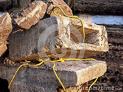 Destroyed light concrete slabs, tied with a thick yellow rope, cable. construction and replacement concept Stock Photo