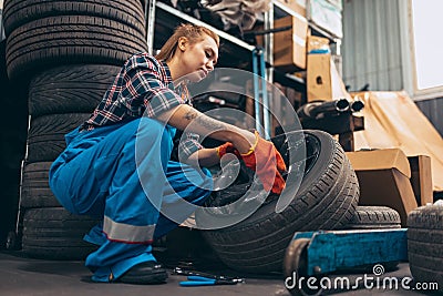 Destroying gender stereotypes. Young woman auto mechanic working at auto service station using different work tools Stock Photo