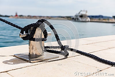 Detail of an anchor rope on a yacht, Stainless steel boat mooring cleat with knotted rope mounted on white yacht deck Stock Photo